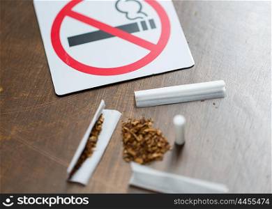 drug use, substance abuse, addiction and no smoking concept - close up of marijuana or handmade cigarette with prohibiting sign