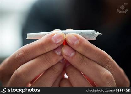 drug use, substance abuse, addiction and people concept - close up of addict hands with marijuana joint