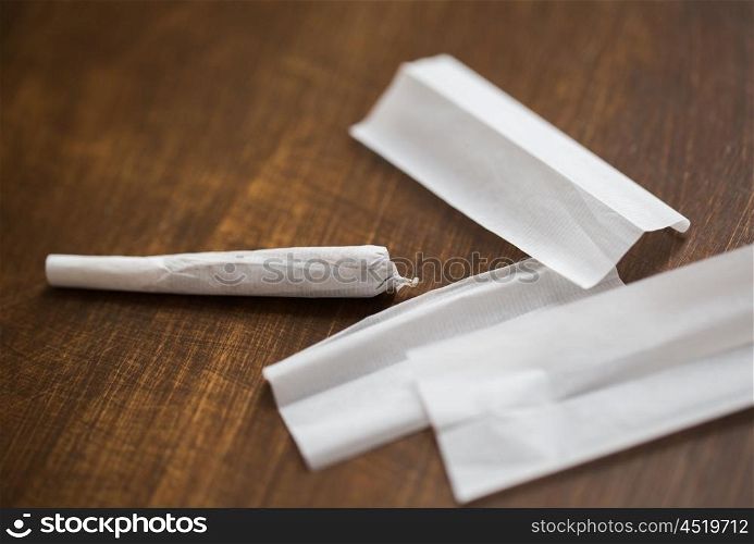 drug use, substance abuse, addiction and smoking concept - close up of marijuana joint and cigarette paper