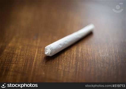 drug use, substance abuse, addiction and smoking concept - close up of marijuana joint or handmade cigarette