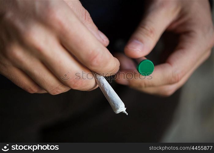 drug use, substance abuse, addiction, people and smoking concept - close up of addict hands with marijuana joint and blunt tube