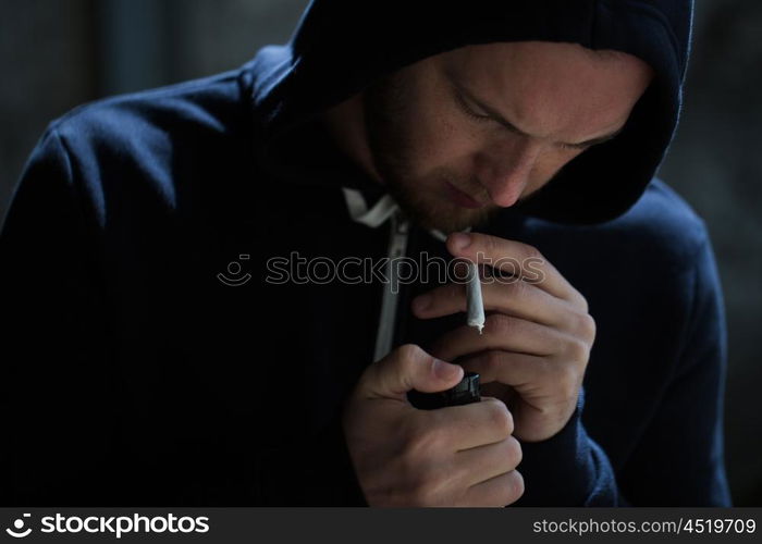 drug use, substance abuse, addiction, people and smoking concept - close up of addict lighting up marijuana joint with lighter