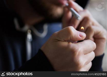 drug use, substance abuse, addiction, people and smoking concept - close up of addict lighting up marijuana joint with lighter