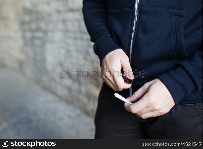 drug use, substance abuse, addiction, people and smoking concept - close up of addict hands with marijuana joint and lighter