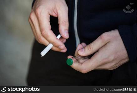 drug use, substance abuse, addiction, people and smoking concept - close up of addict hands with marijuana joint and blunt tube