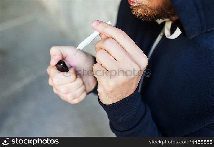 drug use, substance abuse, addiction, smoking and people concept - close up of addict hands with marijuana joint and lighter