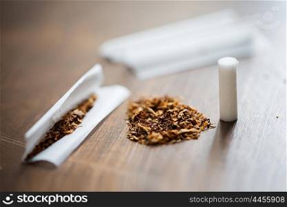 drug use, substance abuse, nicotine addiction and smoking concept - close up of marijuana or tobacco with cigarette paper and filter