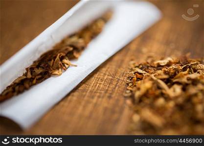 drug use, substance abuse, nicotine addiction and smoking concept - close up of marijuana or tobacco with cigarette paper