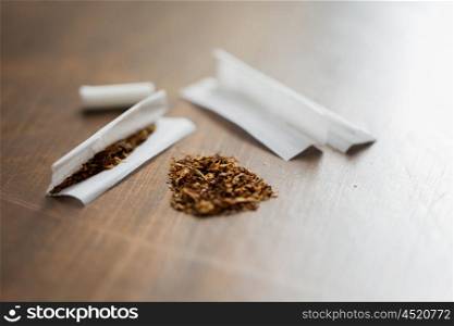 drug use, substance abuse, nicotine addiction and smoking concept - close up of marijuana or tobacco with cigarette paper
