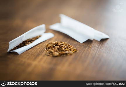 drug use, substance abuse, nicotine addiction and smoking concept - close up of marijuana or tobacco with cigarette paper