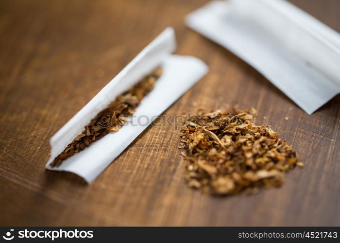 drug use, substance abuse, nicotine addiction and smoking concept - close up of marijuana or tobacco with cigarette paper