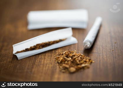 drug use, substance abuse, nicotine addiction and smoking concept - close up of marijuana joint and tobacco