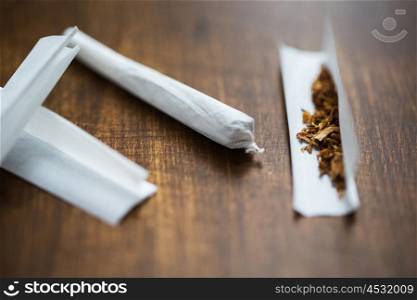 drug use, substance abuse, nicotine addiction and smoking concept - close up of marijuana joint and tobacco