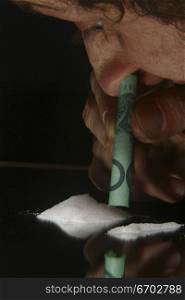 Drugs. cocaine, heroin, speed looking substance. Man Snorting drug with $100 Bill. .