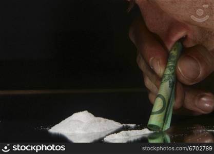 Drugs. cocaine, heroin, speed looking substance. Man Snorting drug with $100 Bill. .