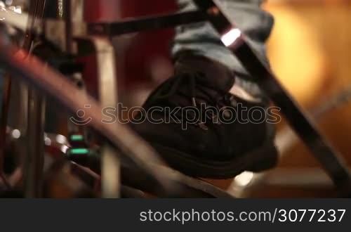Drummer on stage playing kick drum. Closeup musician foot playing base drum pedal at concert in sportlights while rock band performing. Low angle view.