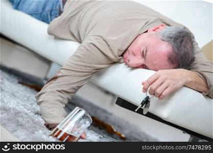 drunk businessman sleeping with beer on a sofa