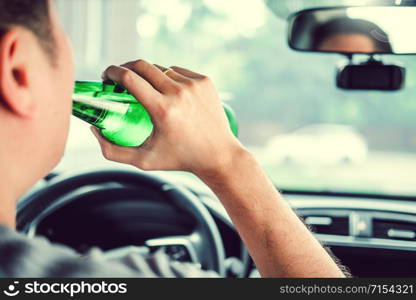 Drunk man driving a car on the road holding bottle beer Dangerous drunk driving concept