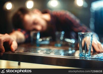 Drunk man sleeps at the bar counter, alcohol addiction. Male person in pub, alcoholism