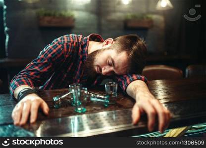 Drunk man sleeps at the bar counter, alcohol addiction. Male person in pub, alcoholism. Drunk man sleeps at bar counter, alcohol addiction