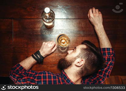 Drunk man sleeps at the bar counter, top view, alcohol addiction. Male person in pub, alcoholism