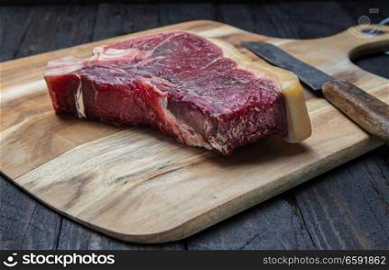Dry aged T-bone steak raw on a wooden board.. Dry aged T-bone steak raw on a wooden board