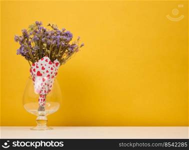 Dry bouquet of wild flowers in a vase on a yellow background, copy space