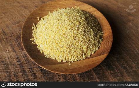 Dry bulgur wheat in wooden bowl isolated Spilled bulgur .. Dry bulgur wheat in wooden bowl isolated Spilled bulgur