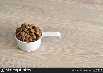 Dry dog food in a white mug isolated on a wooden background