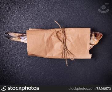 dry fish ram is wrapped in brown kraft paper on a black background