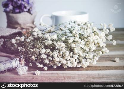 Dry flowers in small bottle and dry bouquet on wooden background