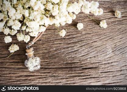 Dry flowers in small bottle on wooden background