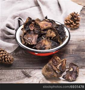 dry forest mushrooms in an iron plate on a gray wooden background, view from the top