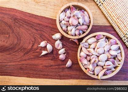 Dry garlic put in wood bowl on brown wooden background. Top view