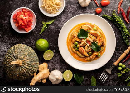 Dry green curry with chicken in white plates on black cement