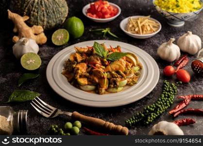 Dry green curry with chicken in white plates on black cement