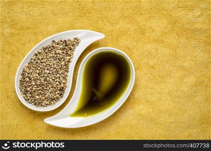 dry hemp seeds andoil in small teardrop bowls against yellow textured paper