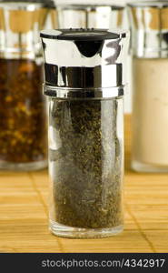 dry mint leaves in a glass jar on different spices background over wooden mat