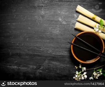 Dry noodles with soy sauce and the cherry branches.On a black wooden background.. Dry noodles with soy sauce and the cherry branches.