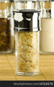 dry onion flakes in a glass jar on different spices background over wooden mat