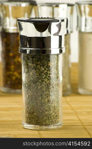 dry parsley in a glass jar on different spices background over wooden mat