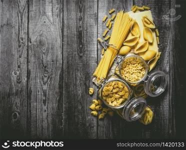 Dry pasta in cans and mixed the pasta with spaghetti. On wooden background. Free space for text . Top view. Dry pasta