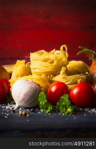 dry pasta with vegetables and seasoning on red wooden background, place for text