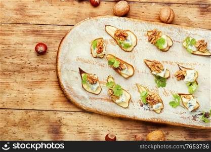 Dry pear,blue cheese and walnut appetizer on cutting board. Dried pear with blue cheese