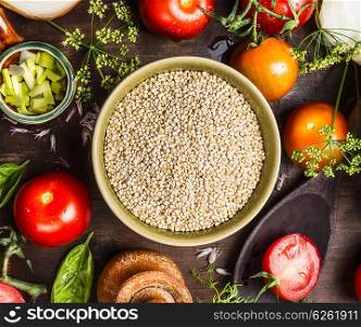 Dry quinoa in bowl with fresh vegetables ingredients, top view, close up