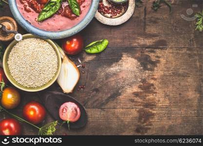 Dry quinoa with tomatoes and cooking ingredients on dark wooden background, top view, border, place for menu or recipe