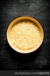 Dry rice in a bowl. On a black wooden background.. Dry rice in a bowl.