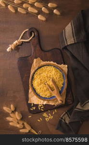Dry risoni pasta in a ceramic bowl on a rustic kitchen countertop.