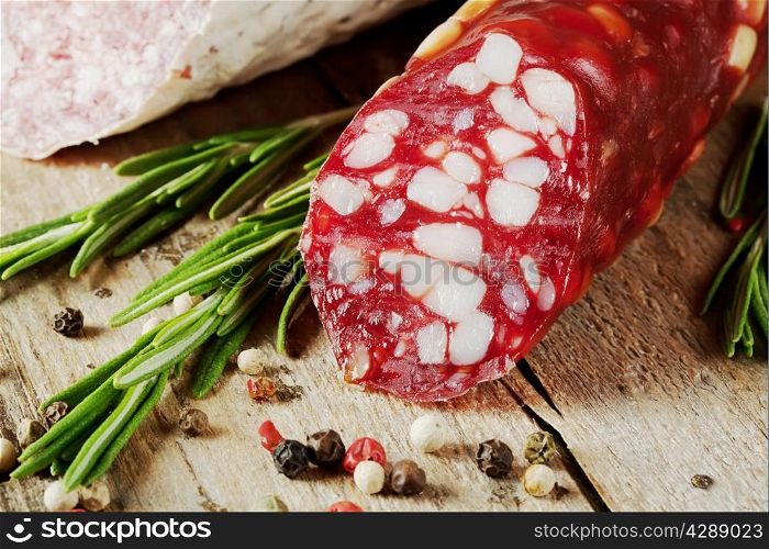 Dry sausage with bacon and rosemary on a wooden table