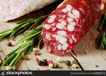 Dry sausage with bacon and rosemary on a wooden table